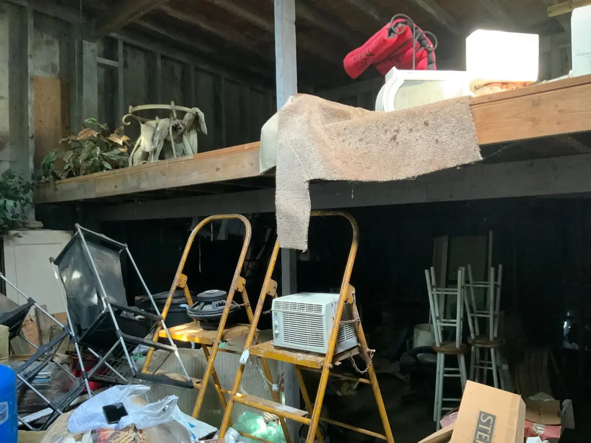 Selling a hoarder house in Bay Shore: garage loft crammed with ladders and old gear