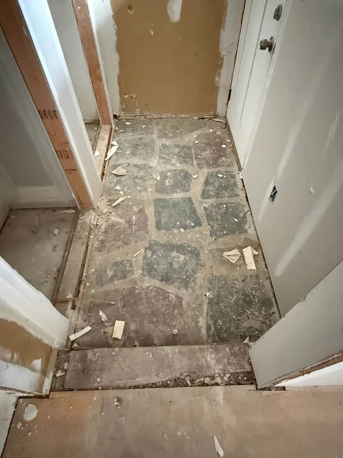 Selling a fire-damaged house in Bay Shore: hallway with old tile scraped off the floor